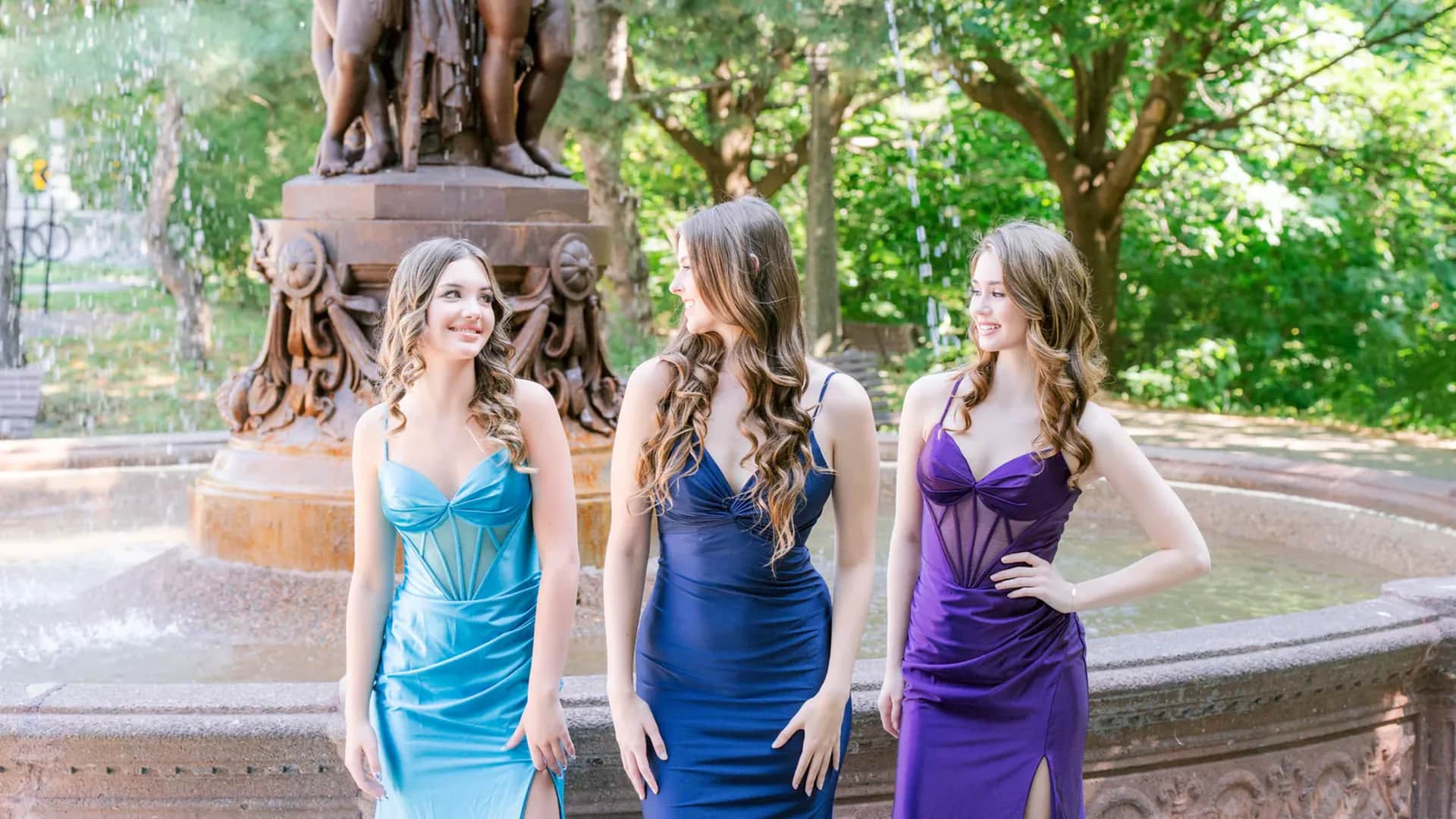 Women dressed in prom dresses in front of fountain