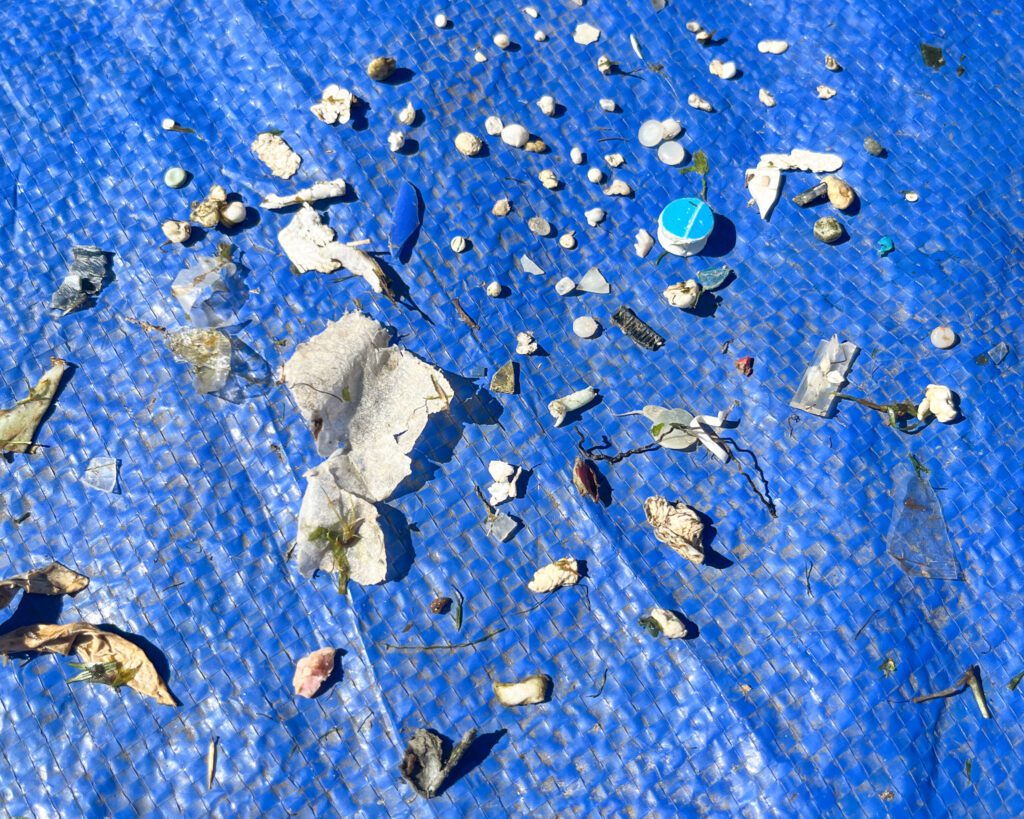 Various microplastics, plastic debris, styrofoam and more displayed on a blue tarp